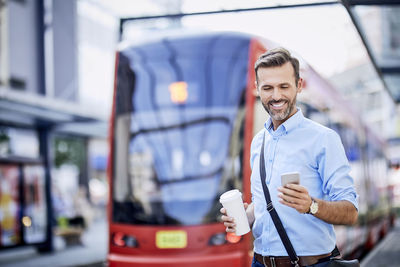 Businessman using phone after getting off public transport