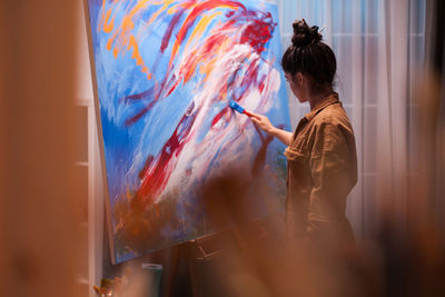 Side view of woman painting at home