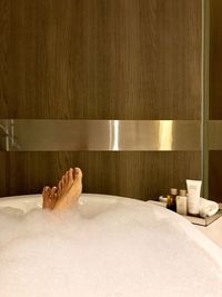 Low section of woman in bathtub in bathroom