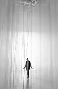 Rear view of silhouette man walking amidst curtains on stage