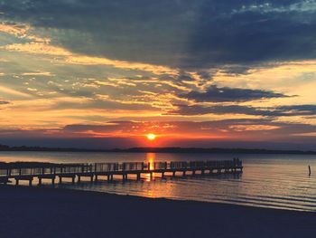 Pier over sea against sky during sunset