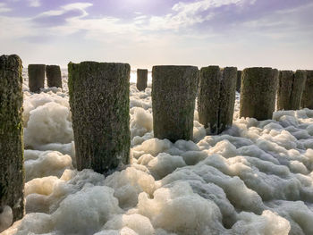 Wave splashing on wooden posts in sea