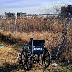 Wheelchair by fence on grassy field