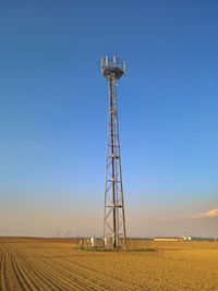 Low angle view of communications tower on field against sky