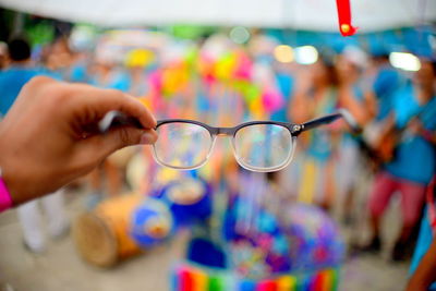 Cropped hand holding eyeglasses during carnival