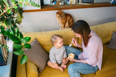 Mom feeds a small child at home with yogurt from a spoon. family concept