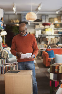 Senior man reading document with digital tablet at store