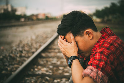 Portrait of young man sitting on railroad track