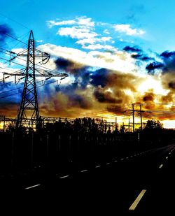 Silhouette trees and electricity pylon against sky