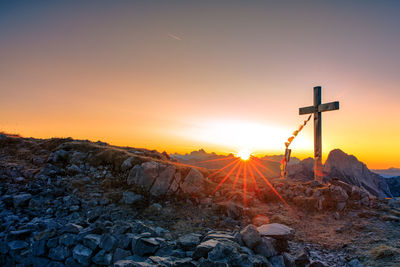 Cross on land against sky during sunset