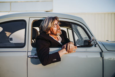 Senior man leaning out of window of vintage car