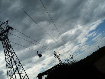 Low angle view of silhouette electricity pylon against sky