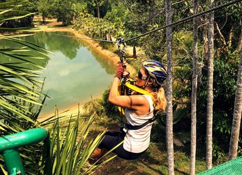 Side view of woman zip lining over trees