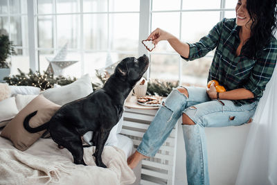 Smiling woman feeding dog at home