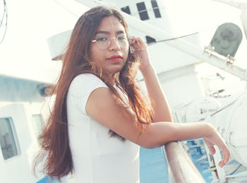 Portrait of young woman standing by railing on boat
