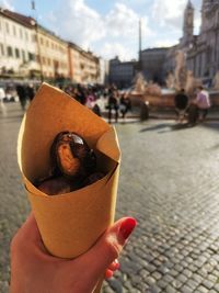 Close-up of hand holding ice cream cone on street