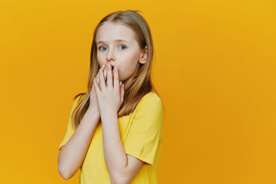 Portrait of young woman against yellow background