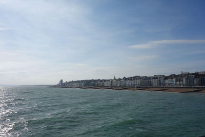 Sea by cityscape against sky