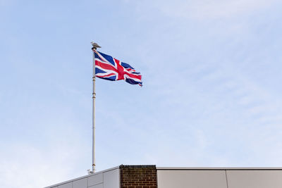 Flag of the united kingdom, flag of england embroidered on blue sky on the roof of a building.