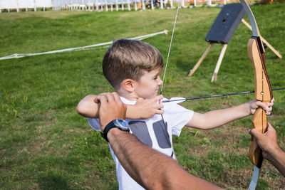 Coach giving archery training to boy outdoor