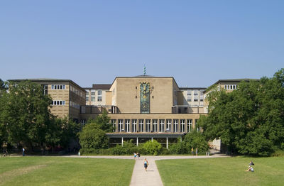 Walkway amidst grassy field leading towards university of cologne