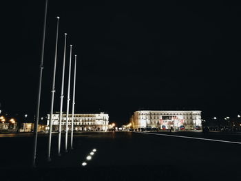 Illuminated buildings by river against sky at night