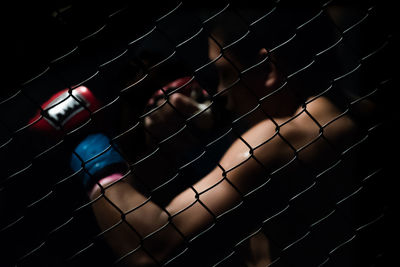 Shirtless boxer seen through chainlink fence