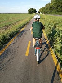 Rear view of boy riding bicycle on road