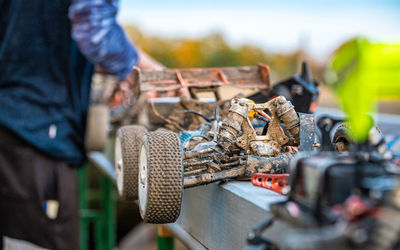 Midsection of man repairing damaged toy car outdoors