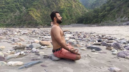 Young man sitting on rock at beach