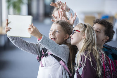 Happy pupils taking a selfie with tablet in school