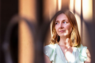 Portrait of a young woman with red hair through the lattice gate.