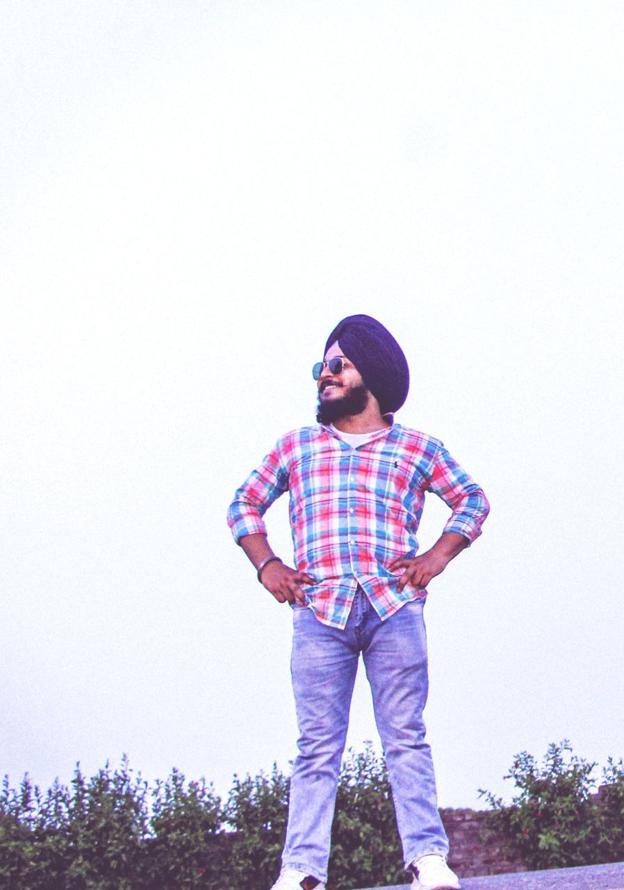 MAN STANDING AGAINST CLEAR SKY