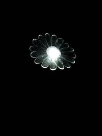 Low angle view of illuminated light bulb against black background