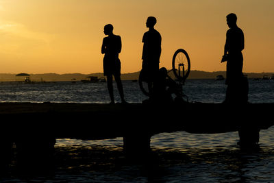 Silhouette people on beach against sky during sunset