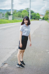 Portrait of smiling young woman standing on road