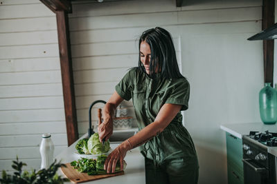 Woman cutting vegetables at kitchen counter