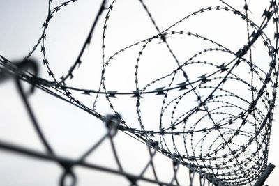 Close-up of barbed wire fence against sky