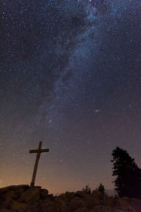 Low angle view of cross on tree against sky at night