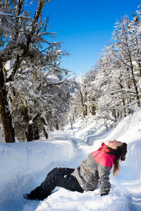 Woman on snowcapped mountain against sky during winter