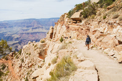 Rear view of people walking on rock by mountain