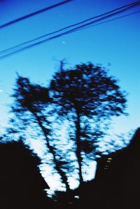 Low angle view of silhouette trees against blue sky