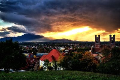 Scenic view of landscape against cloudy sky at sunset