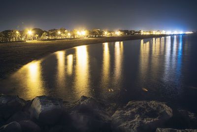 River by illuminated city against sky at night