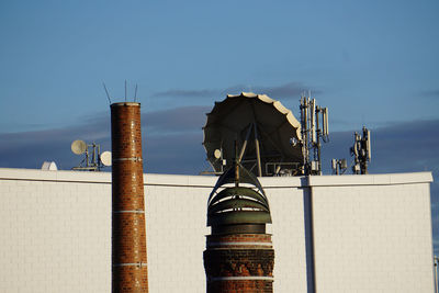 Low angle view of industry by building against sky