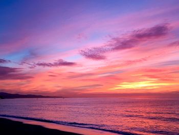 Scenic view of sea against dramatic sky during sunset