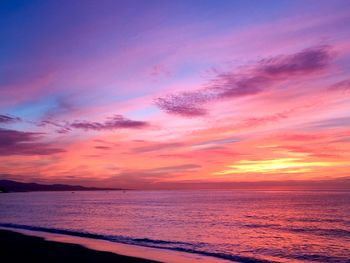 Scenic view of sea against dramatic sky during sunset