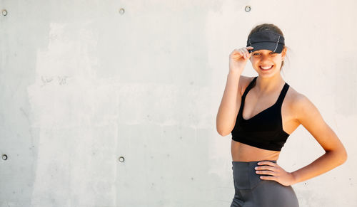 Young woman looking away while standing against wall