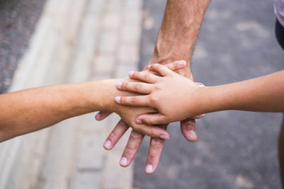 Midsection of friends stacking hands outdoors