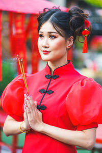 Young woman holding red while standing outdoors